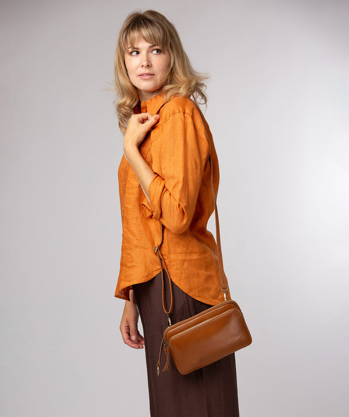 Dark tan leather crossbody bag worn across body styling