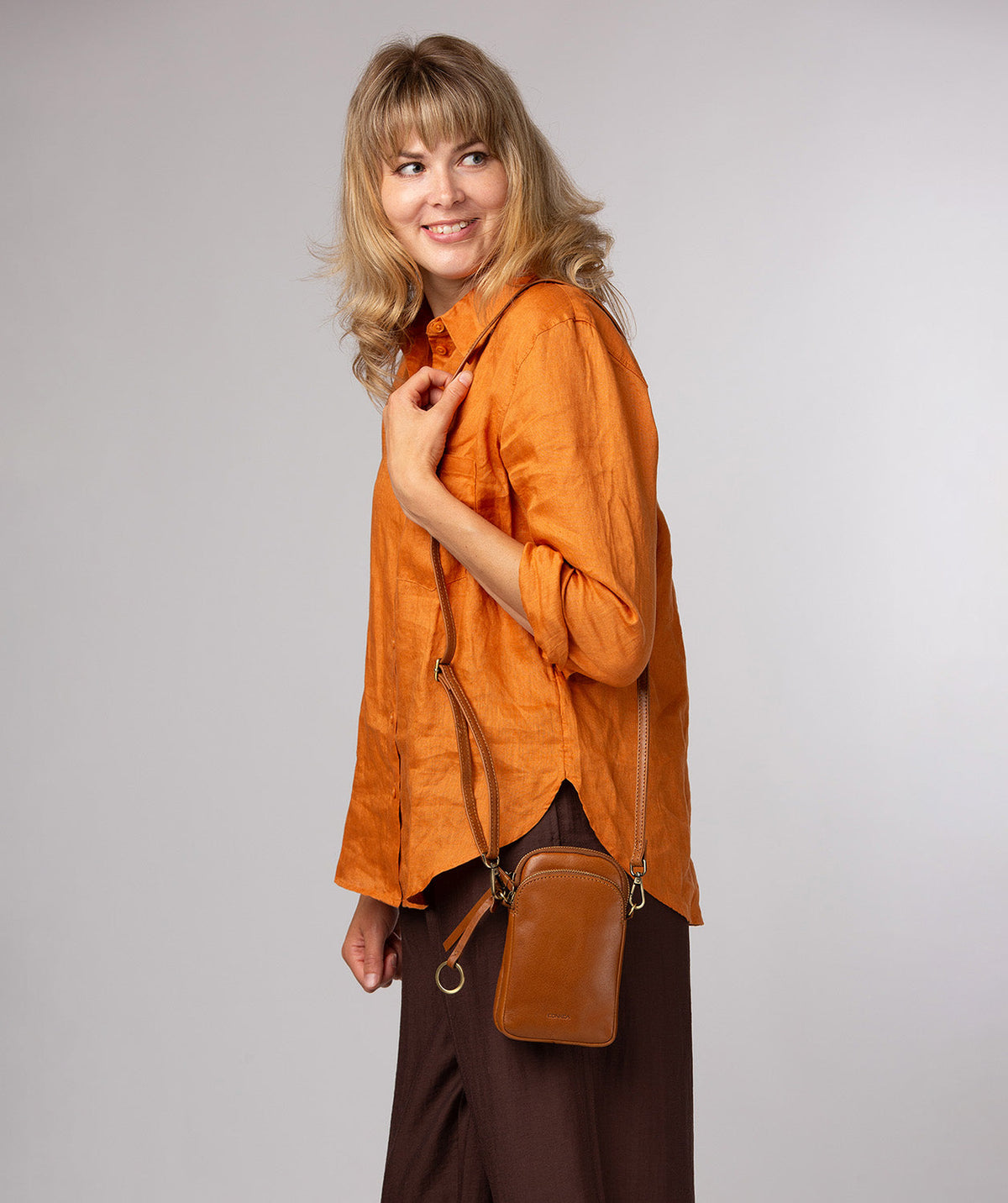 dark tan leather crossbody bag side profile showing brass hardware