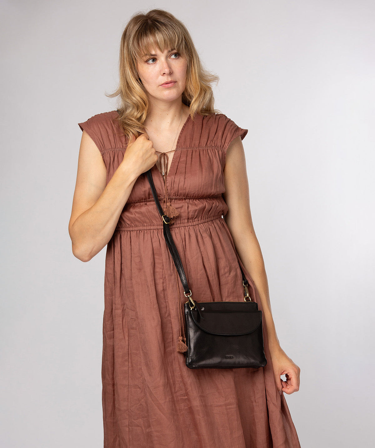 Black leather crossbody bag side profile showing adjustable strap