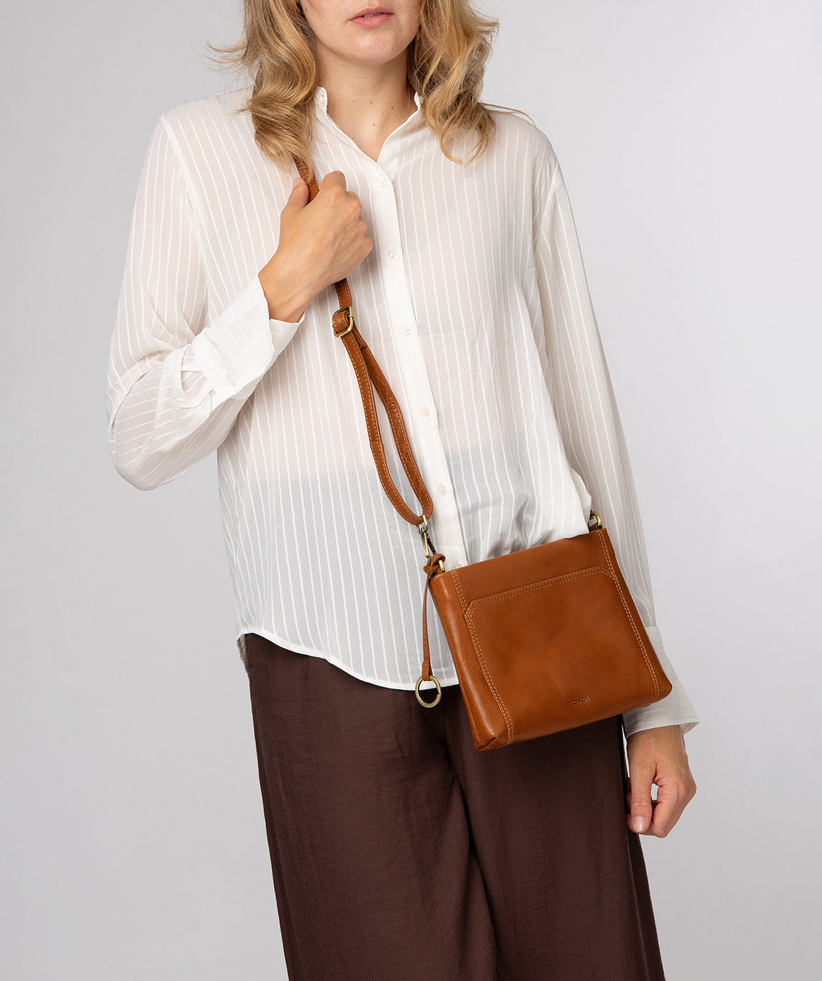 Yew crossbody bag worn across body with adjustable leather strap